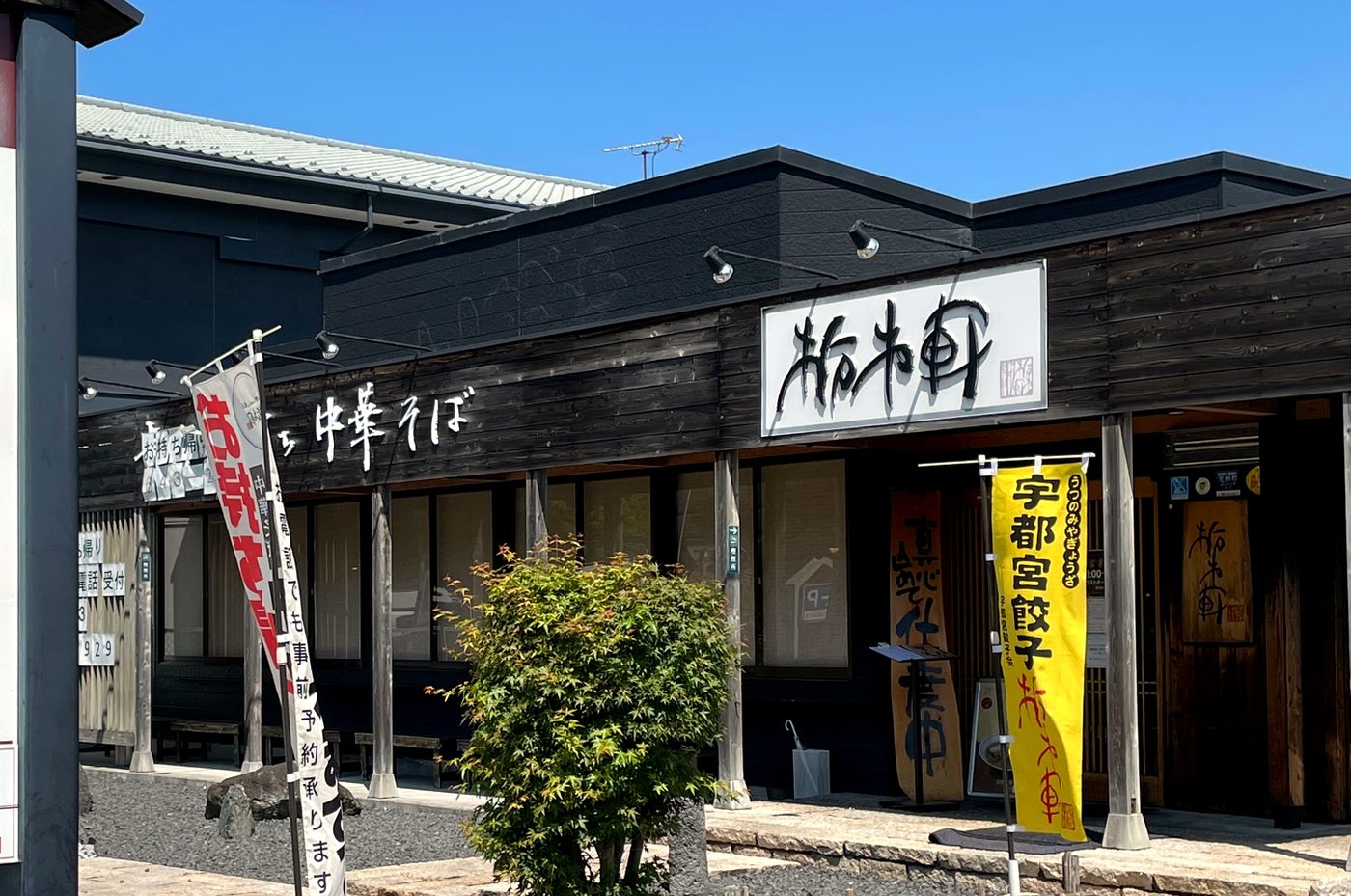 栃木軒の外観。黒い板張りの建物に白い看板と幟が並ぶ